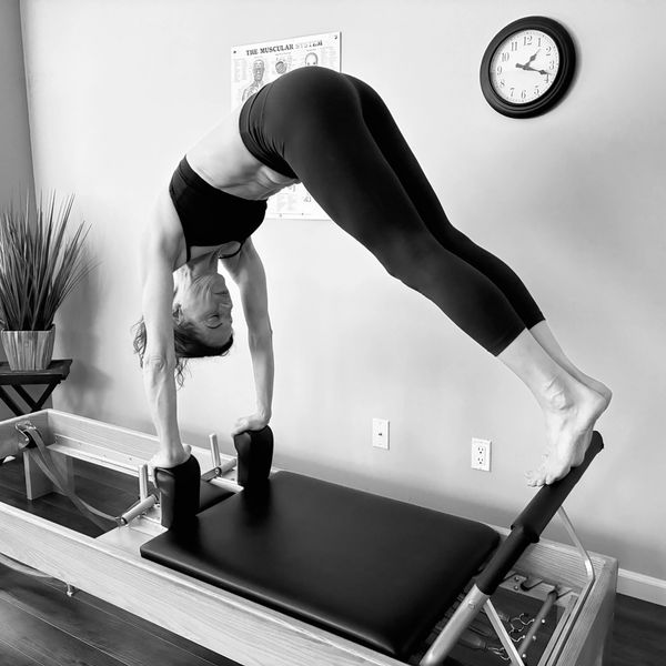Woman performing a handstand on a Pilates reformer.