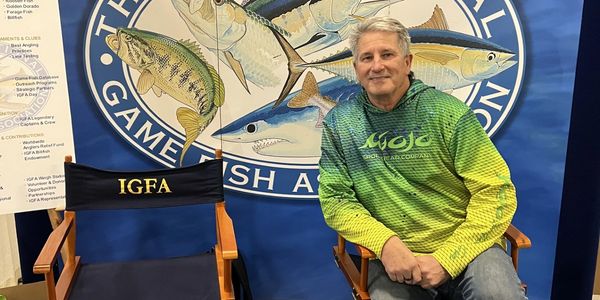 IGFA representative Bill Boyce sitting in a chair looking into audience at a recent fishing and boat