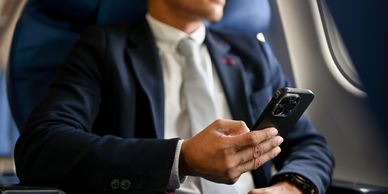 Smart business man sat on a plane checking his mobile phone