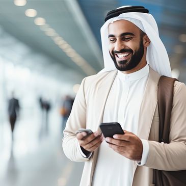 Smiling arab man at an airport using his cellphine