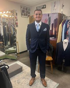 Man in his new navy blue suit with baby blue tie and brown shoes