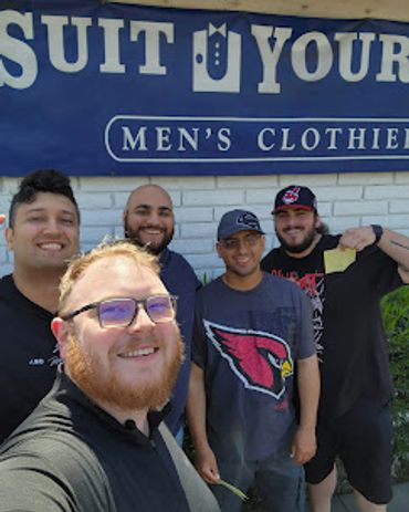 A group of guys standing in front of the suit store