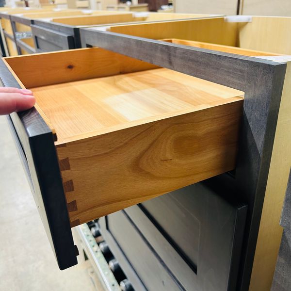 Close-up of a wooden drawer being pulled out in a workshop.