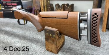 Close-up of a wooden rifle stock resting on a stand indoors.