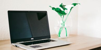 Dell laptop on desk with Lily's in a vase