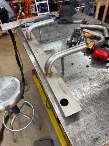 Metalwork setup with bent pipes and tools on a workshop table.