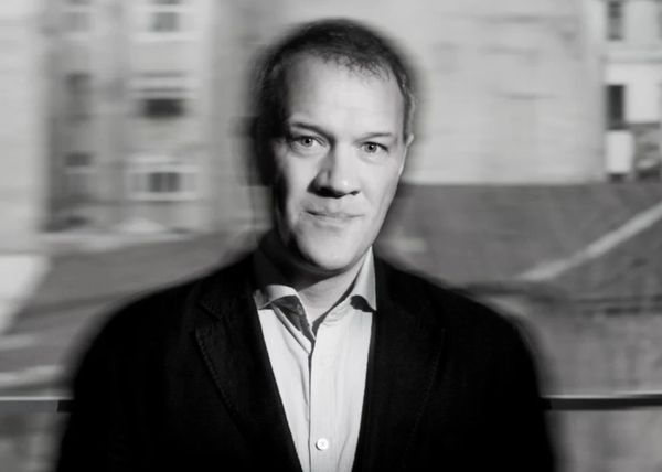 Black and white portrait of a man with a blurred background.