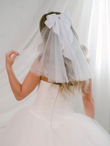 Bride with a white veil and bow, wearing a tulle ballgown wedding dress.