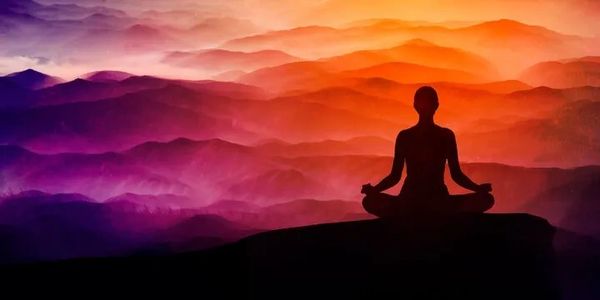 silhouette of a person sitting in meditation (being) with colorful rolling hills in the background