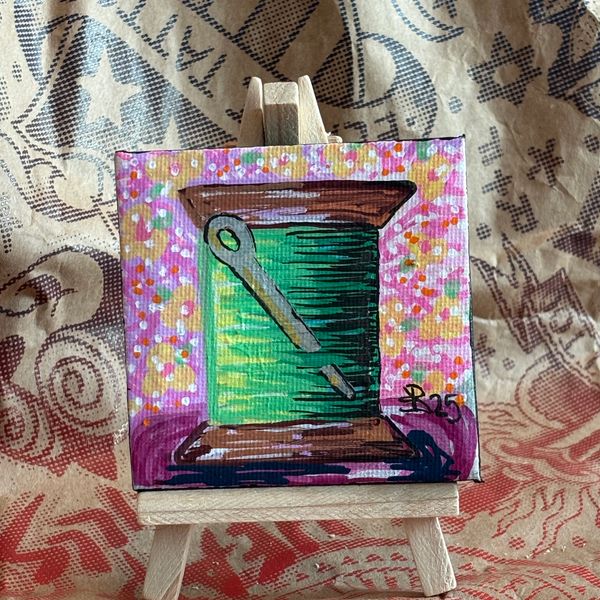 Colorful small painting of a green window with a diagonal key on a mini easel.