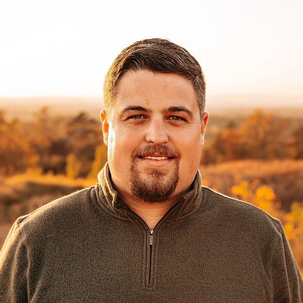 Man with short hair and goatee smiling outdoors.