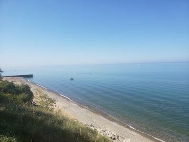 Calm sea with a clear blue sky and a small boat near the shore.
