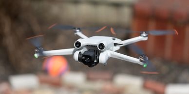 A white drone with four propellers flying outdoors.