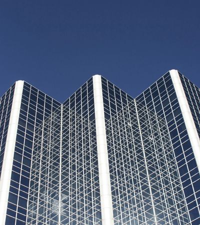 Modern glass skyscraper against a clear blue sky.