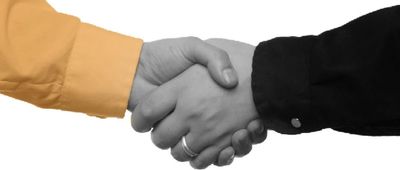 Two people shaking hands, one wearing an orange sleeve, the other in black.