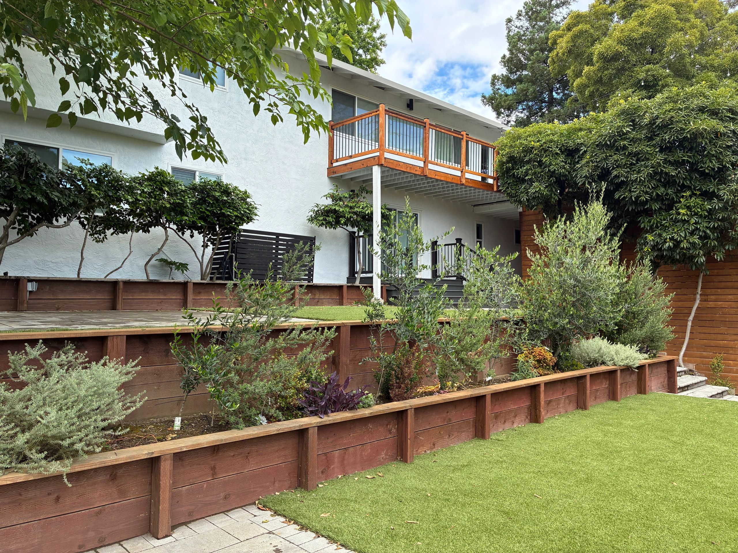 Modern house with wooden balcony and landscaped garden.