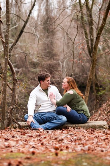 Couple sitting on a bench in a forest, sharing a tender moment.