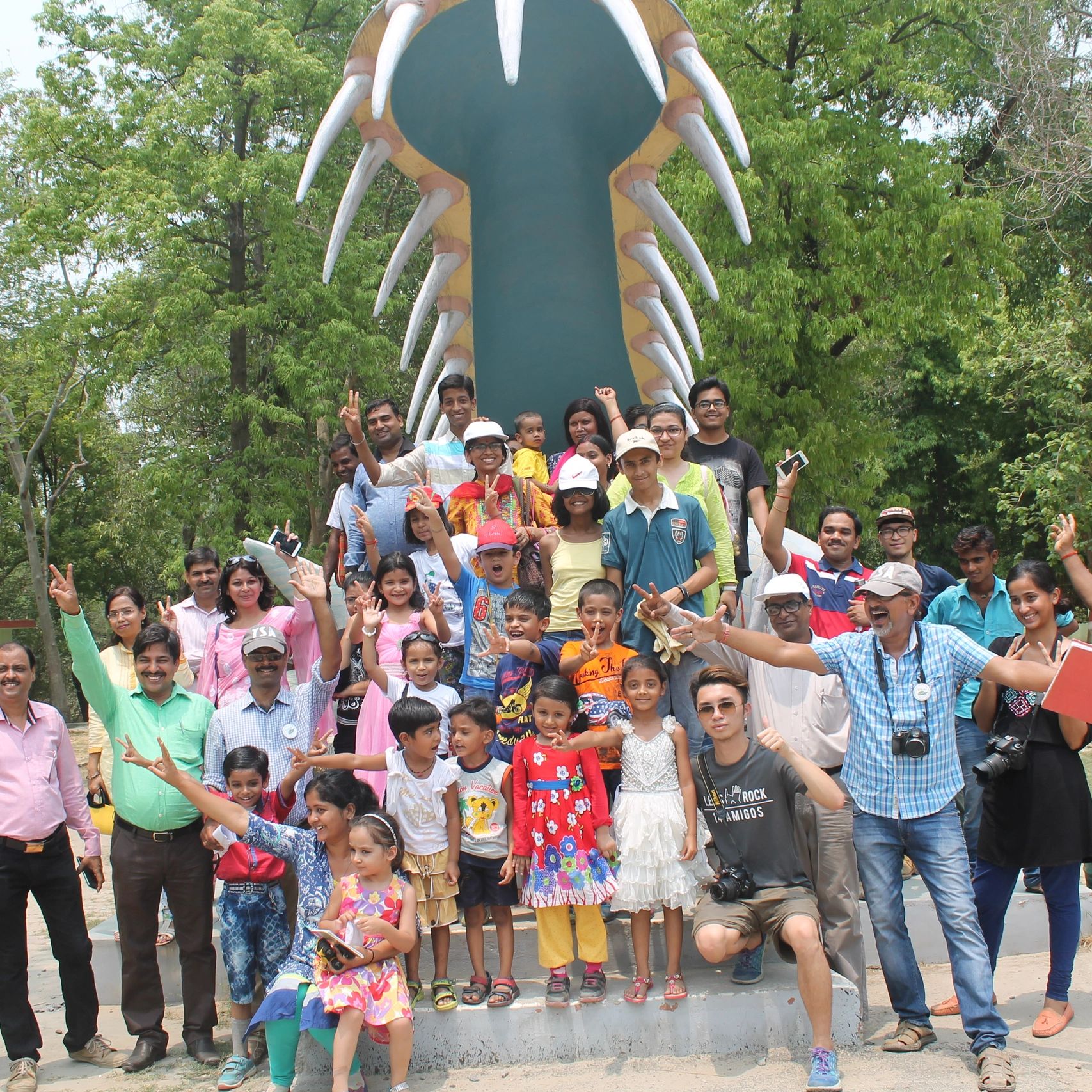 Group of people posing happily in front of a giant snake mouth statue.
