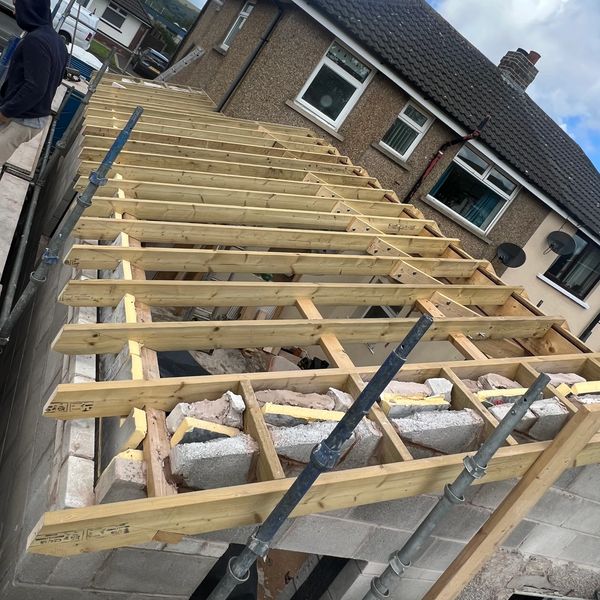 Wooden framework for a roof extension under construction on a house.