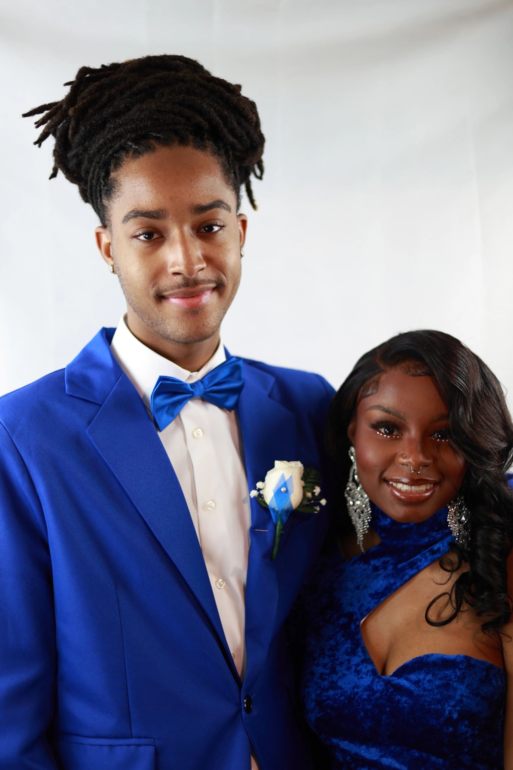 A young couple in matching royal blue formal attire smiling for a photo.