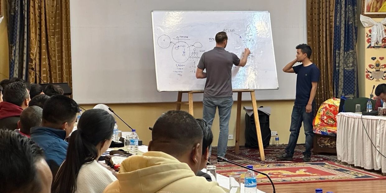 A man writing on a whiteboard during a presentation.
