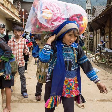 Woman carrying large load on her head in a busy street.