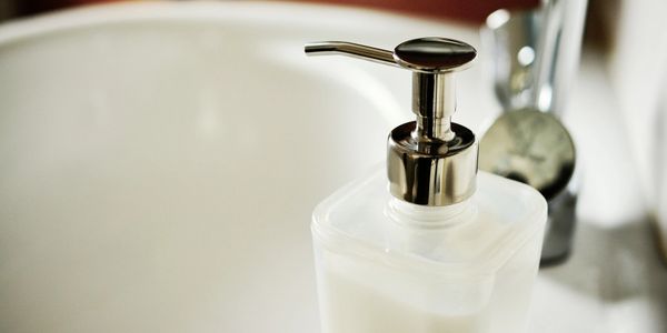 A close-up of a soap dispenser near a bathroom sink.