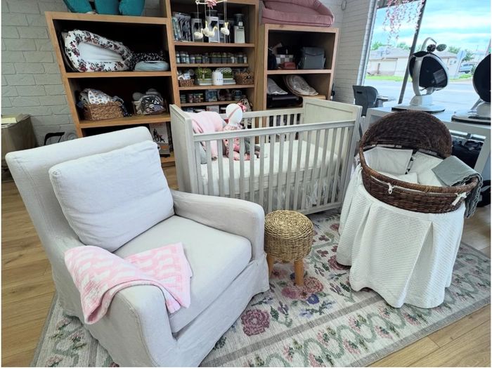 Cozy nursery setup with armchair, crib, and bassinet on a floral rug.