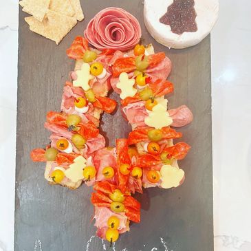 Charcuterie board with meats, cheese, olives, and crackers.