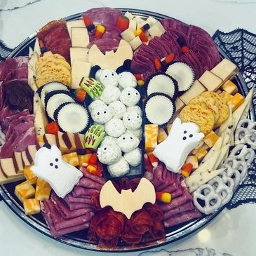 Halloween-themed charcuterie board with ghost and bat decorations.