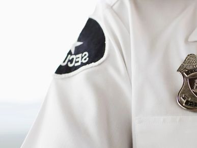 Close-up of a security officer's uniform showing badge and shoulder patch.