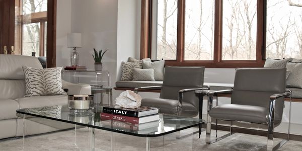 Modern living room with glass coffee table and leather chairs.