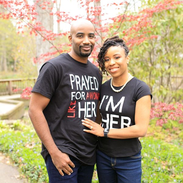 Couple wearing matching message T-shirts standing outdoors with autumn leaves.