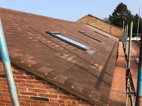 Newly tiled sloping roof with two skylights and scaffolding alongside.