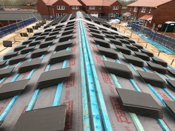 Roof under construction with tiles neatly stacked along the ridge.