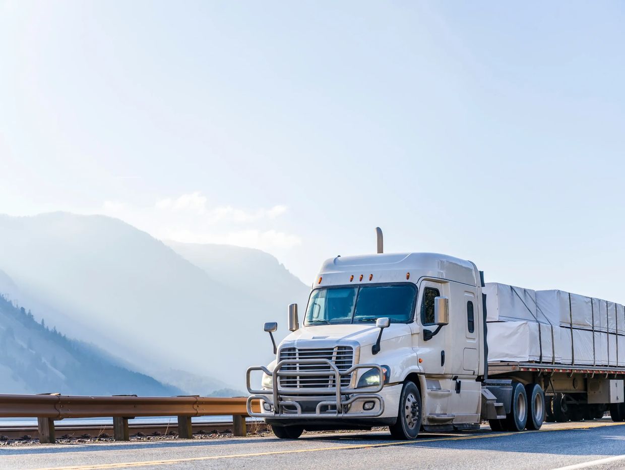 sleeper truck with flatbed trailer hauling freight to receiver