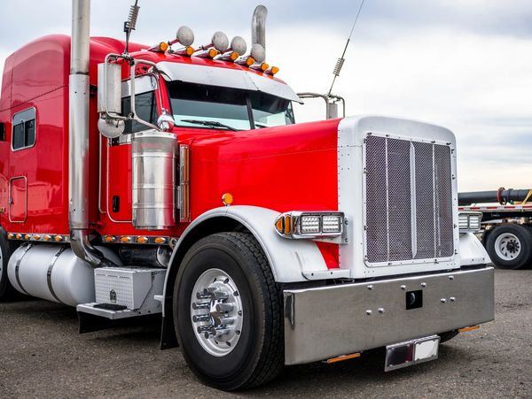 red sleeper cab semi-truck on a layover at a service plaza