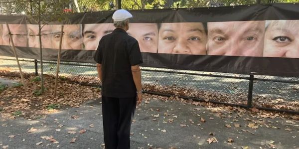 Man observing large close-up portraits outdoors.