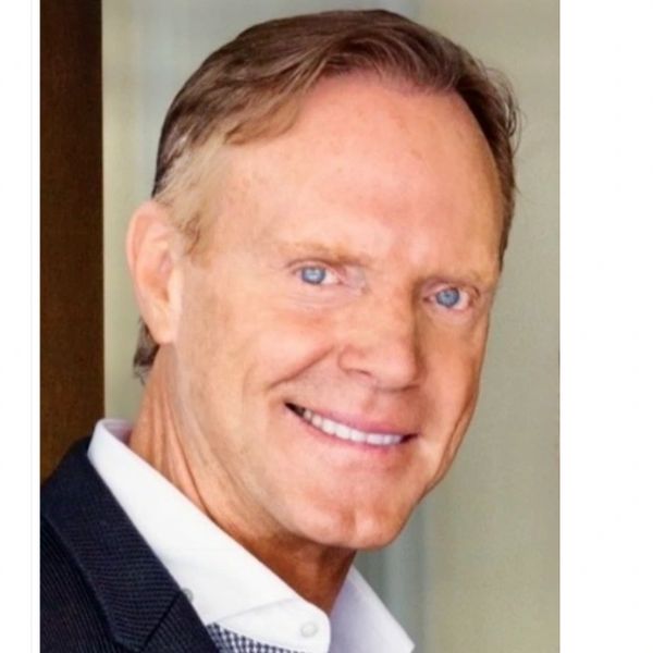 Smiling man in a suit with blue eyes.