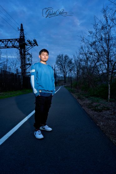 Young boy standing on a road at dusk.