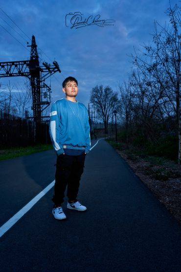 Young man standing on a road at dusk.
