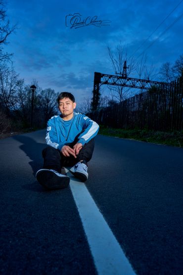 Young man sitting on a road at dusk.