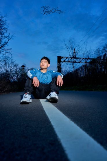 Young man sitting on a road at dusk.
