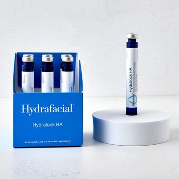 Hydrafacial Hydralock HA skincare vials in a blue box and one vial on a white platform.