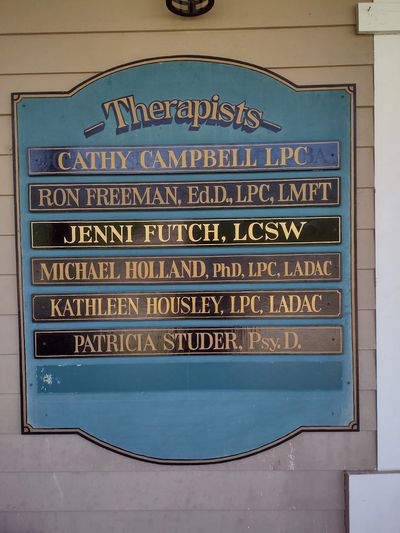 Signboard listing therapists with their qualifications.