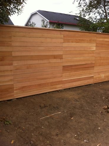 Single board width horizontal fence with faved posts and top cap board. 