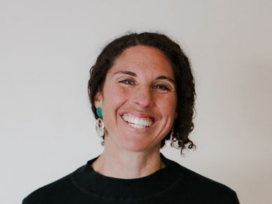 Smiling woman with curly hair and earrings.
