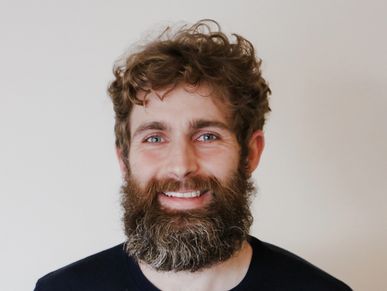 Smiling man with curly hair and a full beard.