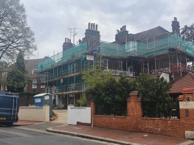 Building under construction with scaffolding and netting.
