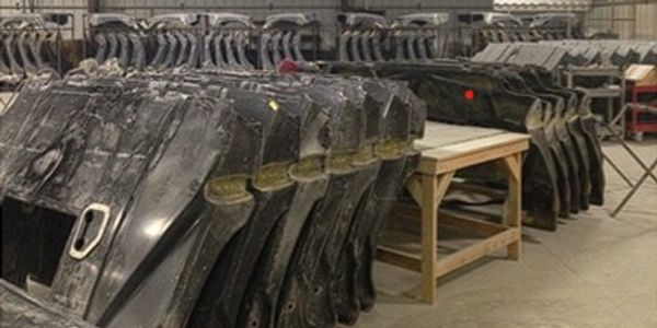Rows of large industrial excavator buckets stored in a warehouse.